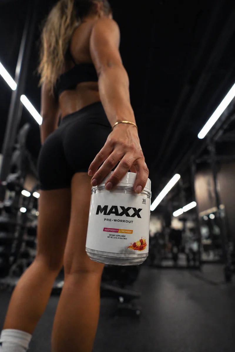 MAXX athlete holding a bottle of MAXX Pre-Workout in the gym